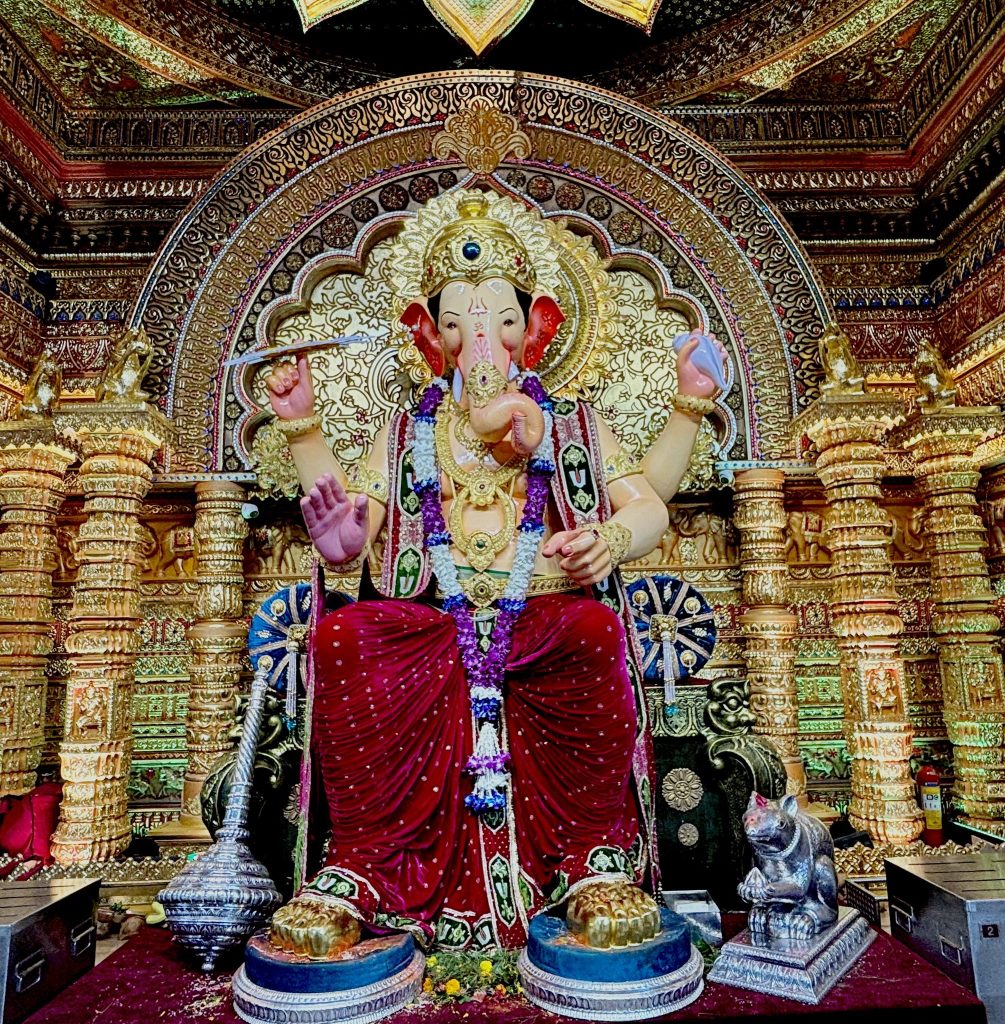Standing in the serpentine queues outside Lalbaugcha Raja, you quickly understand why this pandal has earned the title "Navasacha Ganpati" - the wish-fulfilling Ganesha. Established in 1934 by fishermen and mill workers who prayed to Lord Ganesha for a permanent marketplace, this pandal has grown from humble beginnings to attract over 1.5 million devotees daily during the festival

The Kambli family has been sculpting this iconic idol for over 80 years, and their artistry is nothing short of extraordinary. The 18-20 feet tall idol is crafted entirely by hand without any molds, making each year's creation unique. This year's theme draws inspiration from Tirupati Balaji, creating a divine fusion that represents the unity of different devotional traditions.

What makes Lalbaugcha Raja truly special is not just its size or fame, but the democratic spirit it embodies. Unlike some exclusive pandals, this celebration remains deeply rooted in its working-class origins. The fish vendors and mill workers who founded it continue to manage the celebrations, ensuring that every devotee, regardless of social status, receives equal darshan opportunities.