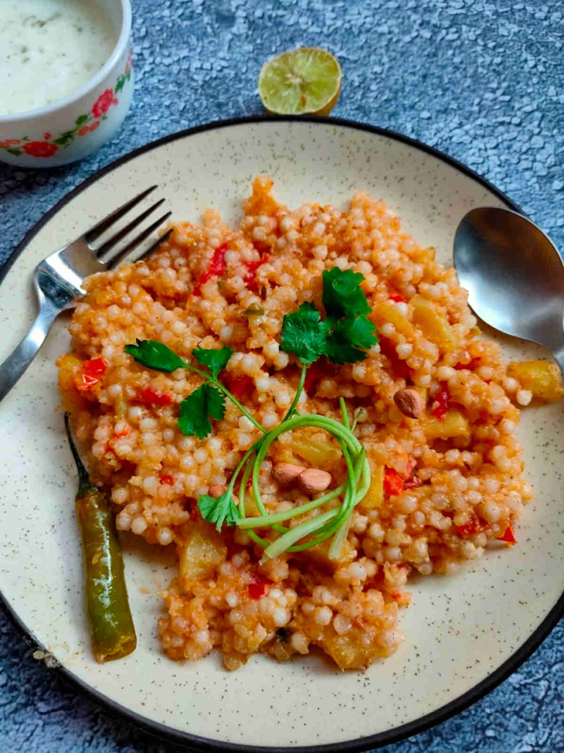 Sabudana khichdi, a traditional Navratri fasting dish made from tapioca pearls, potatoes, and peanuts, garnished with coriander and served with lemon and yogurt
