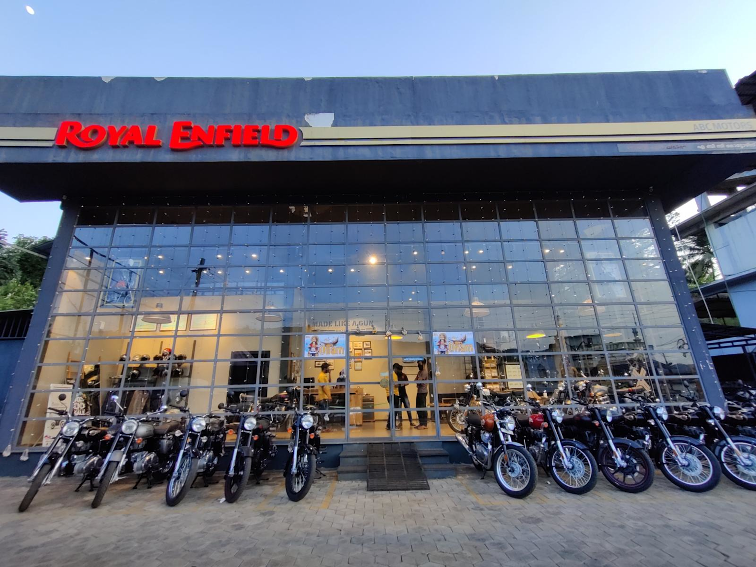 Royal Enfield motorcycle dealership with multiple bike models displayed outside a modern glass-front showroom in India