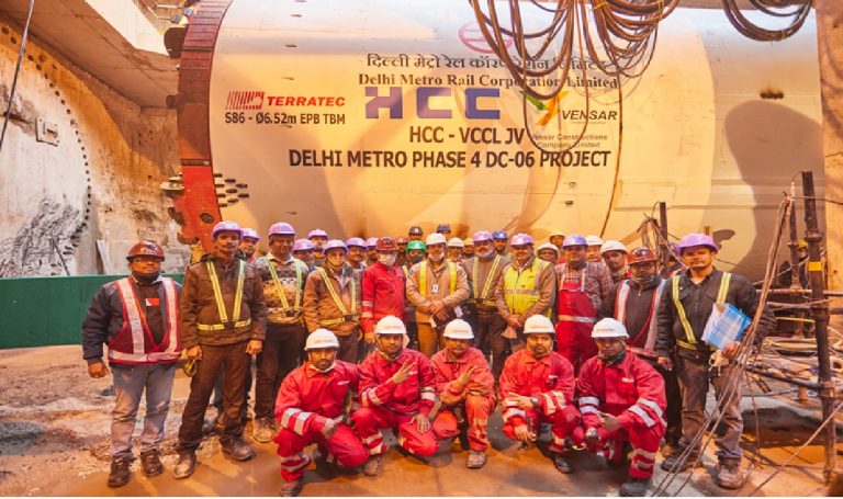 Delhi Metro Phase-IV Corridors to Feature Driverless Trains: A Leap Towards the Future of Urban Transportation The Delhi Metro Rail Corporation (DMRC) has announced a transformative initiative that will redefine urban mobility in India's national capital. The upcoming Phase-IV corridors of the Delhi Metro network will feature state-of-the-art driverless trains, utilizing Unattended Train Operation (UTO) technology to enhance operational efficiency, improve passenger safety, and reduce human intervention in train operations. This ambitious expansion represents a significant milestone in India's journey toward smart, sustainable, and automated public transportation systems. India's first driverless metro train was inaugurated by Prime Minister Narendra Modi on December 28, 2020, on the Magenta Line connecting Janakpuri West to Botanical Garden. Since this historic launch, DMRC has steadily expanded its automated fleet, with 69 driverless trains currently operational across the Pink Line and Magenta Line corridors. The introduction of driverless operations on Phase-IV corridors marks the next chapter in Delhi Metro's technological evolution, positioning it to become the world's second-largest driverless metro network with approximately 160 kilometers of fully automated corridors upon completion. Driverless Delhi Metro train operating on elevated tracks of the Pink Line amid urban surroundings Understanding Unattended Train Operation Technology Advanced Communication-Based Train Control Systems Driverless metro trains operate using sophisticated Unattended Train Operation (UTO) technology, which represents the highest level of automation in rail transportation. This system is classified as Grade of Automation 4 (GoA4) according to international standards defined in IEC 62290-1:2014. At this level of automation, trains can perform all operational functions without any onboard personnel, including starting, accelerating, decelerating, stopping at stations, and conducting safety diagnostics. The technological foundation of driverless operations rests on Communication-Based Train Control (CBTC) systems, which utilize wireless communication technology to transmit real-time data between trains and track equipment. Unlike traditional fixed signal systems that rely on physical signals along railway tracks, CBTC employs continuous bidirectional communication between trains and wayside control centers. This advanced signaling architecture enables precise train location determination with high resolution, independent of traditional track circuits. The CBTC system architecture comprises several critical components working in seamless coordination. Transponders installed at fixed intervals along the tracks wirelessly transmit location information to onboard receivers as trains pass over them. Combined with speed sensors and automated controllers, trains can determine their exact position and automatically calculate optimal movement parameters. This vehicle-centric approach eliminates artificial train separation constraints and allows for minimal safe distances between consecutive trains, significantly increasing line capacity. Operations Control Centre Monitoring All driverless train operations are continuously monitored 24/7 by professionals stationed at the Operations Control Centre (OCC). The OCC provides comprehensive remote visibility and control over the entire metro system, including rolling stock, stations, signals, and tracks, with concourse and platform-level monitoring capabilities. This centralized command hub ensures that automated trains operate safely and efficiently while maintaining the ability to intervene remotely if necessary. DMRC commissioned a state-of-the-art integrated OCC at Metro Bhawan in February 2024 specifically to support Phase-IV operations. This advanced control center will manage operations across the entire DMRC network of approximately 415 kilometers of track, 388 trains, and over 300 stations from one unified location. The facility utilizes advanced CCTV monitoring systems that automatically stream relevant camera feeds to the OCC when passenger emergency alarm devices are activated, ensuring rapid response to any incidents. The fail-safe technology integrated into driverless trains automatically brings trains to a complete stop if any technical anomaly is detected, prioritizing passenger safety above all else. This multi-layered safety architecture, combining automated systems with human oversight from the OCC, has proven highly effective in maintaining Delhi Metro's exemplary safety record on existing driverless corridors. Delhi Metro Phase-IV Project Overview Priority Corridors Under Construction The Delhi Metro Phase-IV project represents one of the most ambitious urban infrastructure undertakings in India, designed to significantly expand connectivity and reduce traffic congestion across the National Capital Region. The comprehensive expansion plan encompasses six corridors spanning approximately 112.32 kilometers with 44 new metro stations scheduled for completion in phases extending through 2029. Three priority corridors are currently under active construction with an expected completion timeline of March 2026, though realistic estimates suggest operational readiness may extend to 2028. These priority corridors include the Majlis Park to Maujpur extension of the Pink Line covering 12.318 kilometers with eight stations, the Janakpuri West to RK Ashram Marg extension of the Magenta Line spanning 28.92 kilometers with 21 stations, and the entirely new Aerocity to Tughlakabad corridor known as the Golden Line, stretching 23.622 kilometers with 15 stations. The Janakpuri West to Krishna Park Extension section, measuring 2.8 kilometers, became the first Phase-IV segment to become operational in January 2025, marking a significant milestone for the expansion project. Construction has achieved substantial progress on the Majlis Park to Jagatpur Village stretch of 4.6 kilometers, which includes three new stations at Burari, Jharoda Majra, and Jagatpur Village, with trial runs having commenced in December 2024. Additional Approved Corridors Beyond the three priority corridors, Delhi Metro has received government approval for three additional corridors that will further extend the network. The Inderlok to Indraprastha corridor will extend the Green Line by 12.377 kilometers, the Lajpat Nagar to Saket G Block corridor will add 8.385 kilometers to the Golden Line network, and the Rithala to Narela to Nathupur (Kundli) corridor will extend the Red Line by 26.463 kilometers into neighboring Haryana. In March 2025, DMRC achieved financial closure for these three remaining corridors through a loan agreement with the Japan International Cooperation Agency (JICA) worth 79,726 million Japanese Yen, approximately ₹4,309.53 crores. This funding will enable tendering work to accelerate, with construction activities scheduled to commence subsequently. The foundation stone for the Rithala-Kundli corridor was laid by Prime Minister Narendra Modi in January 2025, signaling the government's commitment to expanding metro connectivity beyond Delhi's administrative boundaries. Workers and tunnel boring machine at the Delhi Metro Phase 4 underground construction site Project Financing and Rolling Stock Procurement The total estimated cost for Delhi Metro Phase-IV stands at approximately ₹24,948.65 crores, with funding arranged through multiple sources. The Japan International Cooperation Agency (JICA) has extended substantial financial support through Official Development Assistance (ODA) loans totaling approximately ₹12,930.914 crores for the priority corridors. The remaining project costs are being shared between the Central Government contributing ₹4,643.638 crores, the Delhi Government and other sources providing ₹7,374.098 crores. In October 2022, DMRC awarded a significant contract worth ₹2,631.36 crores to Alstom Transport India for the supply of 312 standard gauge metro coaches comprising 52 six-coach train sets for Phase-IV priority corridors. These trains are being manufactured at Alstom's state-of-the-art facility in Sri City, Andhra Pradesh, supporting India's Make in India initiative. The first driverless train set for Phase-IV arrived at the Mukundpur depot in November 2024, where it underwent statutory certification tests before deployment. The 312 coaches are distributed across the three priority corridors as follows: 144 coaches (24 trains) for the Janakpuri West to RK Ashram Marg Magenta Line extension, 90 coaches (15 trains) for the Majlis Park to Maujpur Pink Line extension, and 78 coaches (13 trains) for the new Aerocity to Tughlakabad Golden Line corridor. The Golden Line contract includes comprehensive maintenance services for a period of 15 years, ensuring long-term operational reliability. Advanced Features of Phase-IV Driverless Trains Technical Specifications and Design The new Alstom Metropolis train sets for Delhi Metro Phase-IV incorporate cutting-edge technology and passenger-centric design features. These lightweight trains are constructed from stainless steel with a width of 3.2 meters, optimized for standard gauge track systems. Each six-coach train configuration consists of two Driving Motor Cars (DMC) at both ends and four Trailer Cars (TC) in between, providing a balanced distribution of propulsion power and passenger capacity. The trains are designed with a maximum speed capability of 95 kilometers per hour and an operational speed of 85 kilometers per hour, ensuring rapid transit across the network while maintaining safety margins. The design essentially mirrors the successful Alstom trains currently operating on Mumbai Metro's Aqua Line, demonstrating proven reliability and performance in Indian operating conditions. All Phase-IV trains are equipped with Alstom's advanced CBTC signaling and train control solutions, enabling GoA4 grade automation for fully Unattended Train Operations. This technology allows trains to operate autonomously from depot to passenger service and back, with all critical functions managed by onboard computers communicating continuously with wayside equipment and the central OCC. Enhanced Safety Features Platform Screen Doors (PSDs) represent a critical safety innovation being implemented across all Phase-IV stations. These automated barriers create a physical separation between platform areas and train tracks, opening only when trains are properly positioned at stations. Underground stations will feature full-height PSDs measuring 2.15 meters, while elevated stations will be equipped with half-height PSDs similar to those on existing Pink and Magenta Line stations. Metro platform with automatic platform screen doors enhancing passenger safety The implementation of PSDs serves multiple safety objectives beyond preventing accidental falls or suicide attempts. These systems improve climate control within stations by physically isolating platforms from tunnel areas, enhance security by restricting unauthorized access to tracks, reduce littering on track areas, and improve sound quality of platform announcements by minimizing background noise from tunnels. The synchronization of PSDs with train doors ensures smooth boarding and alighting operations while maintaining operational efficiency. Emergency Escape Doors integrated into the PSD system provide critical safety redundancy. These single-leaf hinged doors open toward the platform side and can be manually operated from the track side if a train fails to stop at the correct position, ensuring passenger safety even during system anomalies. The comprehensive safety architecture combining automated train operations, platform screen doors, and emergency protocols establishes multiple layers of protection for passengers. Energy Efficiency and Sustainability Driverless metro operations contribute significantly to environmental sustainability through multiple mechanisms. The automated systems optimize energy consumption by precisely controlling acceleration and braking profiles, eliminating the variability inherent in human operation. Artificial Intelligence algorithms calculate optimal deceleration and acceleration times, allowing trains to start and stop with pinpoint accuracy while minimizing energy expenditure. Delhi Metro has earned international recognition for its environmental initiatives, becoming the first railway project in the world certified by the United Nations to receive carbon credits for reducing Greenhouse Gas (GHG) emissions. Through its innovative regenerative braking process, whenever trains apply brakes, three-phase traction motors act as generators producing electrical energy that returns to overhead electricity lines for use by other accelerating trains in the same service line. This system reduces overall electricity requirements by approximately 30 percent. The modal shift from private vehicles to metro transportation has resulted in Delhi Metro helping reduce pollution levels in the city by an estimated 630,000 tonnes annually. DMRC currently meets about 35 percent of its total energy needs from renewable sources, primarily solar energy, with an ambitious target to increase this proportion to 50 percent by 2031. The combination of automated operations, regenerative braking, renewable energy utilization, and reduced vehicular emissions positions Delhi Metro as a model for sustainable urban transportation. Current Driverless Operations and Future Expansion Magenta and Pink Line Success Stories The Delhi Metro's existing driverless operations on the Magenta and Pink Lines have demonstrated exceptional performance and reliability since their implementation. The Magenta Line achieved full GoA4 unattended operations in May 2025, with all train operators completely removed from the system. This milestone was reached through a carefully phased implementation strategy spanning several years, beginning with the removal of cab partition doors and driving consoles while retaining train operators, progressing to allowing operators anywhere within trains, then reducing operator presence to alternate trains only, and finally eliminating operators entirely. The Pink Line commenced its automation journey in March 2025 and reached Stage II by June 2025, with full driverless operations expected within a few months thereafter. Once both lines achieve complete automation, Delhi Metro will operate 97 kilometers of fully driverless corridors out of its total 395-kilometer network in the Delhi-NCR region, positioning it among the world's largest driverless metro systems. Currently, 43 driverless trains operate on the Pink Line and 26 on the Magenta Line under the UTO system. According to DMRC officials, the implementation of driverless operations has significantly enhanced operational efficiency by improving coach availability for service and eliminating manual pre-induction inspection processes, thereby reducing the workload on train operators while ensuring smoother service delivery. Record-Breaking Ridership Performance The Delhi Metro's reliability and efficiency have driven consistently increasing passenger numbers, demonstrating strong public confidence in the system. On August 8, 2025, DMRC achieved its highest-ever single-day ridership with 8,187,674 passenger journeys recorded across all operational corridors. This milestone surpassed the previous record of 7.87 million journeys set in November 2024. To accommodate the surge in travel demand ahead of the Rakshabandhan festival, DMRC operated 92 additional train trips on August 8 and scheduled 455 extra trips for August 9. These impressive ridership figures reflect passengers' growing trust in Delhi Metro's reliability, punctuality, and seamless connectivity across the Delhi-NCR region. The automated operations on driverless corridors have contributed to this success by enabling higher service frequencies, reducing delays caused by human factors, and maintaining consistent schedule adherence. The flexibility of driverless operations allows DMRC to quickly adjust service levels in response to real-time demand, optimizing resource utilization during peak and off-peak periods. Path to World's Second-Largest Driverless Network Upon completion of Phase-IV, Delhi Metro will operate driverless trains across extended sections of the Pink and Magenta Lines, as well as the entirely new Golden Line corridor from Aerocity to Tughlakabad. This expansion will result in approximately 160 kilometers of fully automated metro corridors operating under GoA4 standards, establishing Delhi Metro as the world's second-largest driverless metro network after Singapore. This remarkable achievement positions Delhi Metro at the forefront of global urban rail automation. Among the elite 7 percent of metro networks worldwide capable of operating trains autonomously, Delhi Metro's extensive driverless infrastructure demonstrates India's technological capabilities and commitment to modernizing public transportation. The success of Delhi Metro's automation initiatives has inspired other Indian cities including Mumbai, Bangalore, and Kolkata to pursue similar driverless technologies for their metro systems. Advantages of Driverless Metro Operations Operational Efficiency and Flexibility Driverless train operations deliver substantial improvements in operational efficiency across multiple dimensions. Automated systems eliminate response time variabilities inherent in human control, optimizing running times by increasing average speeds and reducing station dwell times. This enhanced precision enables trains to operate at minimum safe separations, dramatically increasing line capacity without requiring additional infrastructure investments. The predictability of automated operations creates unprecedented operational flexibility. Operators can automatically park trains and maintain them in idle mode indefinitely, quickly respond to service changes without requiring human drivers to be constantly present, and seamlessly adjust service frequencies based on real-time demand patterns. During periods of high passenger volume, train lengths can be doubled through automatic coupling controlled remotely from the control center, maximizing capacity utilization. Train regulation systems optimize energy consumption and reduce maintenance costs through smoother driving standards and optimal acceleration and braking profiles. The elimination of manual driving variability results in more consistent wear patterns on rolling stock and infrastructure components, extending equipment lifespan and reducing maintenance requirements. These efficiency gains translate directly into lower operational costs, making driverless systems economically attractive despite higher initial capital investments. Enhanced Safety and Reliability Automated train operations significantly enhance passenger safety through multiple mechanisms. Advanced monitoring systems equipped with sophisticated sensors and algorithms continuously monitor train operations in real-time, making autonomous decisions faster than human operators to minimize errors and prevent accidents. The elimination of human factors such as fatigue, distraction, or misjudgment removes major sources of operational risk that have historically contributed to railway accidents. The fail-safe design philosophy embedded in driverless systems ensures that any detected anomaly automatically triggers protective responses, bringing trains to controlled stops before potentially hazardous situations can develop. Sensor data combined with predictive analytics enables optimized maintenance scheduling, identifying potential equipment failures before they occur and further improving system reliability. The continuous monitoring from the OCC provides an additional safety layer, with human experts able to intervene remotely if automated systems encounter unexpected scenarios. The safety record of Delhi Metro's existing driverless operations validates these technological advantages. Since the introduction of UTO services on the Magenta and Pink Lines, these corridors have maintained exemplary safety standards while handling millions of passenger journeys. The integration of platform screen doors with automated train operations creates a comprehensive safety ecosystem that effectively prevents platform accidents, a leading cause of casualties on metro systems worldwide. Environmental and Economic Benefits The environmental advantages of driverless metro operations align closely with India's commitment to achieving net-zero emissions by 2070. Automated trains reduce energy consumption through precise speed control and optimized acceleration/braking profiles, lowering overall carbon footprints by reducing congestion and improving throughput. The regenerative braking systems employed by Delhi Metro recover kinetic energy during deceleration, feeding it back into the electrical grid for use by other trains, resulting in approximately 30 percent energy savings. Delhi Metro's modal shift impact demonstrates the broader environmental benefits of efficient public transportation. Every passenger choosing metro over private vehicles contributes to reducing roughly 100 milligrams of carbon dioxide emissions per 10-kilometer trip. The TERI study found that metro rail passengers save about 32.38 grams of CO₂ per kilometer compared to road vehicle travel. With over 8 million daily passenger journeys, the cumulative emission reductions are substantial, contributing meaningfully to air quality improvement in the National Capital Region. From an economic perspective, driverless operations reduce long-term operational expenditures through lower staffing requirements, reduced energy costs, optimized maintenance scheduling, and improved asset utilization. While initial capital investments for automation technology are significant, the lifecycle cost advantages become apparent over the 30-40 year operational lifespan of metro systems. The ability to increase service frequencies without proportional cost increases makes driverless systems particularly attractive for high-density urban corridors experiencing growing demand. Construction Progress and Engineering Achievements Tunneling Breakthroughs and Innovations Delhi Metro Phase-IV construction has achieved multiple significant tunneling milestones utilizing advanced Tunnel Boring Machine (TBM) technology. In July 2025, DMRC completed a 792-meter underground tunnel between Tughlakabad and Tughlakabad Railway Colony on the Golden Line corridor using a 91-meter-long TBM operating at an average depth of 18 meters. This achievement marked one of several parallel tunnel segments being constructed simultaneously across Phase-IV corridors. In June 2025, another major breakthrough occurred at Vasant Kunj Metro Station with the completion of a 1,550-meter tunnel between Kishangarh and Vasant Kunj on the Aerocity-Tughlakabad corridor. This tunnel was excavated at an average depth of 22.86 meters, ranging between 15.48 and 30.25 meters, requiring the installation of 1,105 precast concrete rings with an inner diameter of 5.8 meters. The parallel tunnel on this stretch had been completed in March 2025, demonstrating the coordinated progress across multiple construction packages. The longest tunneling drive of Phase-IV was completed by Afcons Infrastructure in late 2024, boring a 2.65-kilometer stretch between Tughlakabad Airforce and Maa Anandmayee Marg station using a 105-meter-long TBM at a depth of 16 meters. This challenging drive required frequent cutter replacements to penetrate hard rock formations, with the tunnel alignment carefully planned to avoid passing beneath heritage structures. The tunnel utilized approximately 1,894 precast tunnel rings manufactured at a mechanized casting yard using steam curing systems to achieve early concrete strength. All underground tunneling for Phase-IV employs the Earth Pressure Balancing Method (EPBM), a proven technology that allows controlled excavation through varied soil and rock layers while maintaining ground stability. This technique is particularly valuable for underground construction in densely populated urban areas where minimizing surface disturbance and preventing ground subsidence are critical priorities. Continuous monitoring of ground movement during excavation ensures structural stability and public safety throughout the construction process. Overall Project Status As of mid-2025, Delhi Metro Phase-IV construction has achieved approximately 70 percent completion on several critical corridors. The 4.6-kilometer stretch between Majlis Park and Jagatpur Village on the Pink Line extension is approaching completion, with three stations at Burari, Jharoda Majra, and Jagatpur Village nearing readiness. Trial runs on this segment commenced in December 2024, and the section awaits final statutory approvals and safety certifications before opening to passengers. Significant progress has been recorded on the Aerocity-Tughlakabad Golden Line corridor, with three major tunnel breakthroughs completed within a two-month period during early 2025. Of the total 65.2 kilometers approved for the priority corridors, approximately 40.1 kilometers comprise underground sections, with the Aerocity-Tughlakabad corridor accounting for 19.34 kilometers of subterranean construction. The remaining portions utilize elevated structures, which generally progress faster than underground segments due to fewer geological constraints. While the original deadline for Phase-IV priority corridors was December 31, 2024, DMRC has revised its completion target to March 2026. However, realistic assessments by industry observers suggest that full operational readiness may extend to 2028 due to the complexity and scale of remaining work. The COVID-19 pandemic and subsequent labor shortages significantly impacted construction timelines during 2020-2021, creating delays that continue to influence the project schedule. Transforming Urban Mobility in Delhi-NCR Connectivity and Accessibility Improvements Delhi Metro Phase-IV will fundamentally transform urban mobility across the National Capital Region by providing last-mile connectivity to emerging residential and employment hubs. The expansion will add 44 new metro stations across the priority corridors, significantly enhancing accessibility for communities in North, West, South, and East Delhi. Areas such as Burari, Sonia Vihar, Bhajanpura, Vasant Kunj, Chhatarpur, and Tughlakabad will gain direct metro access for the first time. The strategic routing of Phase-IV corridors addresses critical connectivity gaps in Delhi's existing metro network. The Golden Line creates a vital north-south link connecting the Violet and Airport Express Lines at their termini, providing seamless access to Indira Gandhi International Airport from southern residential areas. The extended Magenta Line will connect central Delhi's RK Ashram Marg area with western suburbs, improving accessibility for commuters traveling between these regions. The 29 existing interchange stations within Delhi Metro's network enable passengers to transfer between lines seamlessly, creating a highly connected transportation web. Phase-IV will further enhance this interconnectivity, allowing commuters to reach virtually any corner of Delhi-NCR through convenient metro connections. This comprehensive coverage encourages modal shift from private vehicles to public transportation, reducing road congestion and improving overall urban mobility. Socioeconomic Impact The expansion of Delhi Metro generates substantial socioeconomic benefits extending beyond transportation convenience. Improved connectivity reduces travel times significantly, with Delhi Metro saving an estimated 269 million hours of travel time for passengers annually. This time savings translates directly into enhanced productivity, better quality of life, and increased economic opportunities for residents across the metropolitan region. Property values in areas gaining metro connectivity typically experience appreciation as accessibility improves, benefiting homeowners and stimulating real estate development. Commercial activity around metro stations flourishes through increased foot traffic and improved accessibility for customers and employees. The construction phase itself generates significant employment across skill levels, from engineering and technical roles to construction labor, contributing to economic growth. The environmental benefits of increased metro ridership extend to public health improvements through better air quality. Delhi's chronic air pollution problems are significantly exacerbated by vehicular emissions, with private vehicles contributing 40-50 percent of the city's air pollution. By encouraging modal shift to metro transportation, Phase-IV will help reduce vehicular emissions, contributing to cleaner air and better health outcomes for Delhi's residents. Challenges and Future Outlook Technical and Operational Considerations The implementation of driverless operations on Phase-IV corridors presents technical challenges requiring careful management. The integration of new driverless trains with existing infrastructure and signaling systems demands meticulous planning and extensive testing to ensure seamless operations. The commissioning phase for CBTC systems typically involves substantial work scopes, significant equipment quantities, multiple stakeholders, and complex coordination requirements. Cybersecurity emerges as a critical concern for automated metro systems reliant on wireless communications and computer control. The CBTC architecture's dependence on continuous data exchange between trains and wayside equipment creates potential vulnerabilities requiring robust security protocols. DMRC must implement comprehensive cybersecurity measures to protect against potential threats while maintaining system reliability and performance. Public acceptance of driverless technology represents another important consideration. While Delhi Metro's existing driverless operations on the Magenta and Pink Lines have built public confidence, some passengers may initially feel uncomfortable boarding trains without visible operators. Clear communication about safety features, continuous OCC monitoring, and the proven track record of existing driverless services will be essential for building public trust. Integration with Broader Transportation Ecosystem Delhi Metro Phase-IV must integrate effectively with other transportation modes to maximize its impact on urban mobility. Seamless connections with bus services, auto-rickshaws, cycle-sharing systems, and pedestrian infrastructure are essential for providing true last-mile connectivity. The development of multimodal transportation hubs at major metro stations can facilitate smooth transfers between different transportation modes, encouraging comprehensive public transit adoption. The integration of Delhi Metro with regional rail systems serving neighboring states represents a strategic priority for the National Capital Region. Coordinated timetabling, integrated ticketing systems, and physical connectivity between Delhi Metro and rail networks serving Uttar Pradesh, Haryana, and Rajasthan would create a comprehensive regional transportation system. Phase-V planning efforts already envision extending metro connectivity to cities in neighboring states, building on the foundation established by Phase-IV. Smart city initiatives provide opportunities for deeper integration of metro operations with urban management systems. Real-time passenger information systems, mobile ticketing applications, and integration with navigation platforms enhance user experience and convenience. Data analytics from automated metro operations can inform urban planning decisions, helping authorities understand travel patterns and optimize transportation infrastructure investments. Conclusion The introduction of driverless trains on Delhi Metro Phase-IV corridors represents a transformative advancement in India's urban transportation infrastructure. By implementing cutting-edge Unattended Train Operation technology featuring Communication-Based Train Control systems, platform screen doors, and comprehensive safety protocols, DMRC is establishing new benchmarks for metro operations in India and globally. The expansion will add approximately 112 kilometers of new metro lines with 44 stations, significantly enhancing connectivity across Delhi-NCR while positioning Delhi Metro as the world's second-largest driverless metro network with 160 kilometers of fully automated corridors. The operational advantages of driverless systems—including enhanced safety, improved efficiency, greater flexibility, reduced energy consumption, and environmental sustainability—demonstrate the compelling benefits of automation technology. With construction progressing steadily toward the revised March 2026 completion target for priority corridors, Delhi Metro Phase-IV promises to revolutionize urban mobility for millions of residents. The successful implementation of driverless operations will serve as a model for other Indian cities pursuing metro automation, contributing to India's broader vision of sustainable, technology-driven urban development. As Delhi Metro continues its journey toward becoming a world-class automated metro network, the Phase-IV expansion exemplifies the transformative potential of investing in modern, sustainable public transportation infrastructure. The driverless trains soon to operate across these new corridors will not merely transport passengers—they will carry Delhi-NCR toward a cleaner, more connected, and more efficient urban future.